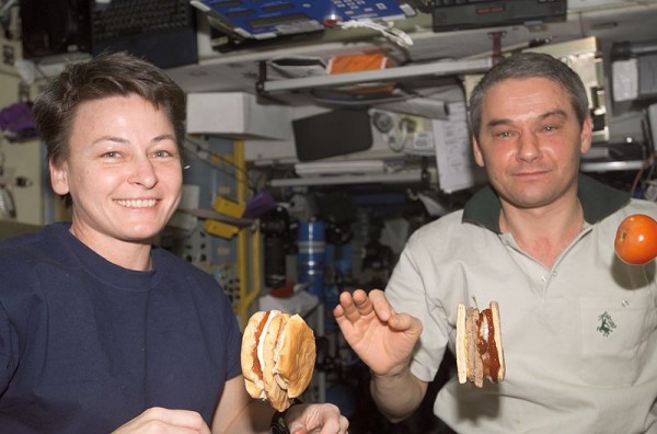 View of Astronaut Peggy Whitson, flight engineer (left) and Cosmonaut Valery Korzun, commander (right), eating a meal in the Service Module (SM)/Zvezda. Tomato and hamburger are floating. Photo by NASA.