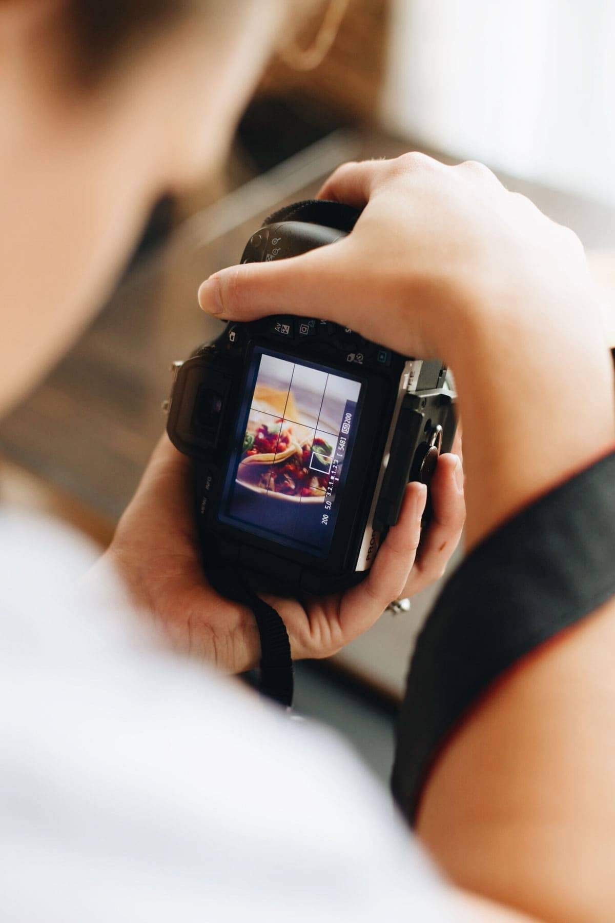 Person holding a camera taking a photo of food.