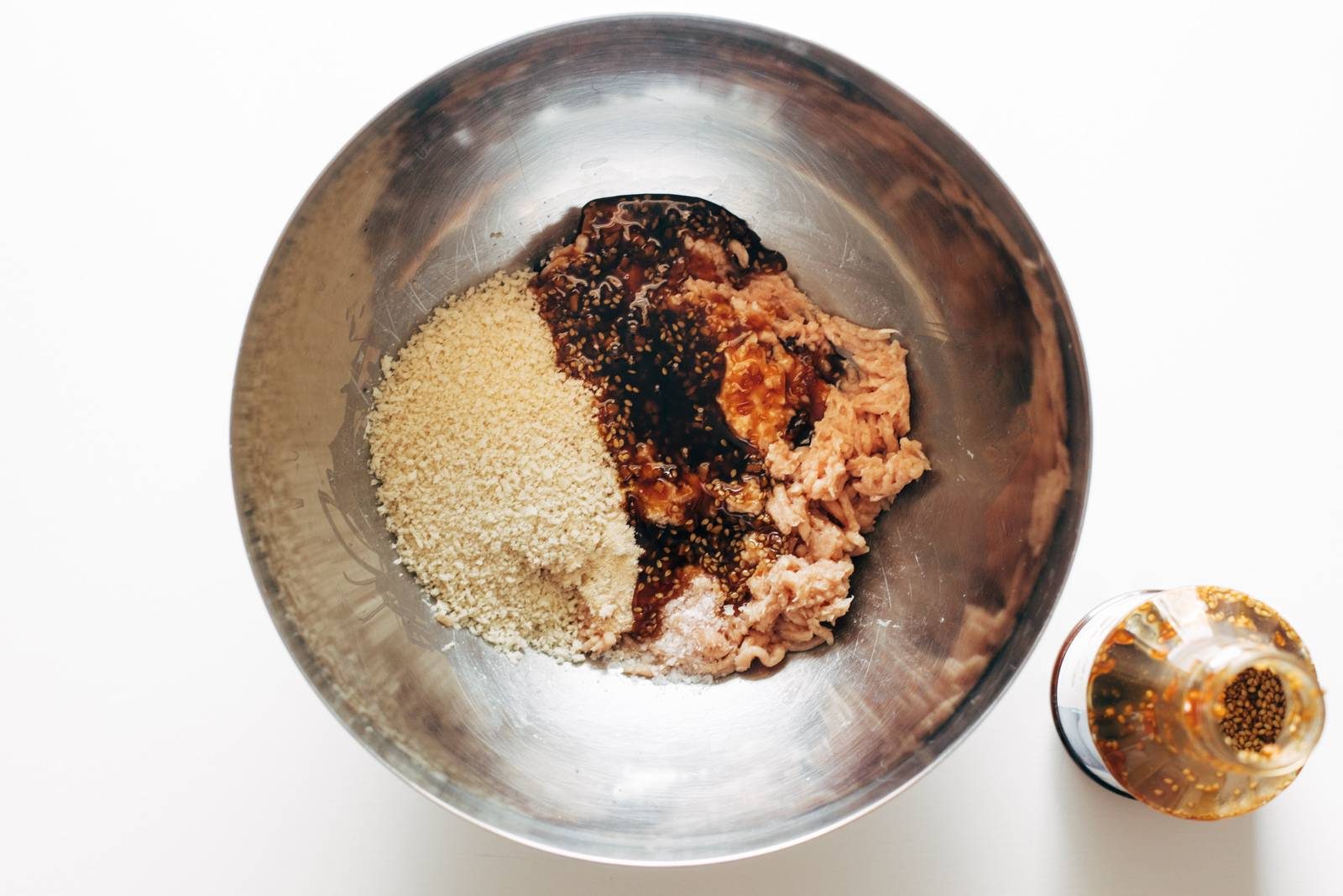 Mixing together ingredients for chicken burgers in a bowl.