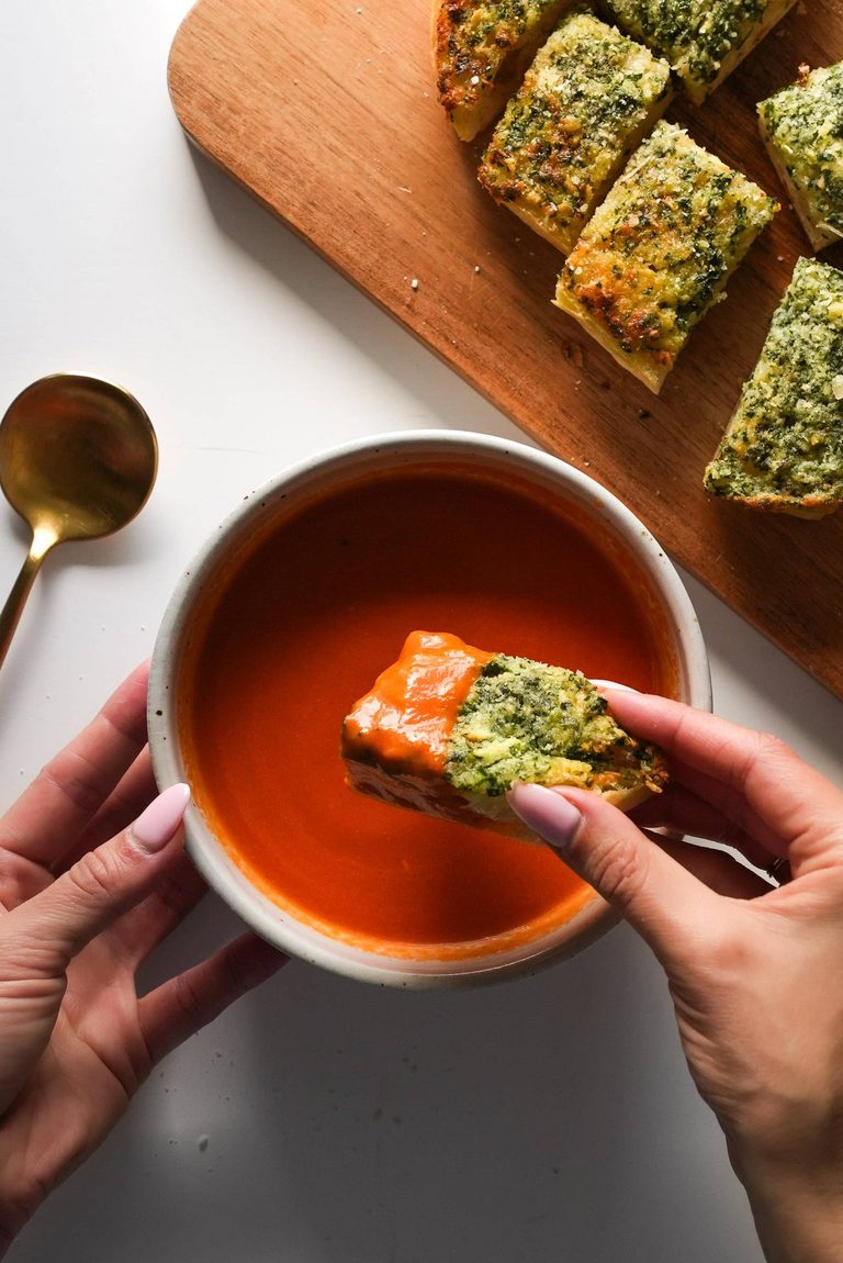 Tomato soup in a bowl with garlic bread.