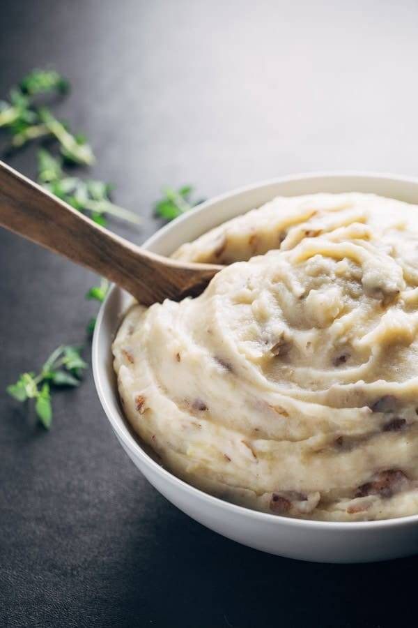 Garlic Mashed Potatoes in a mixing bowl with a wooden spoon.